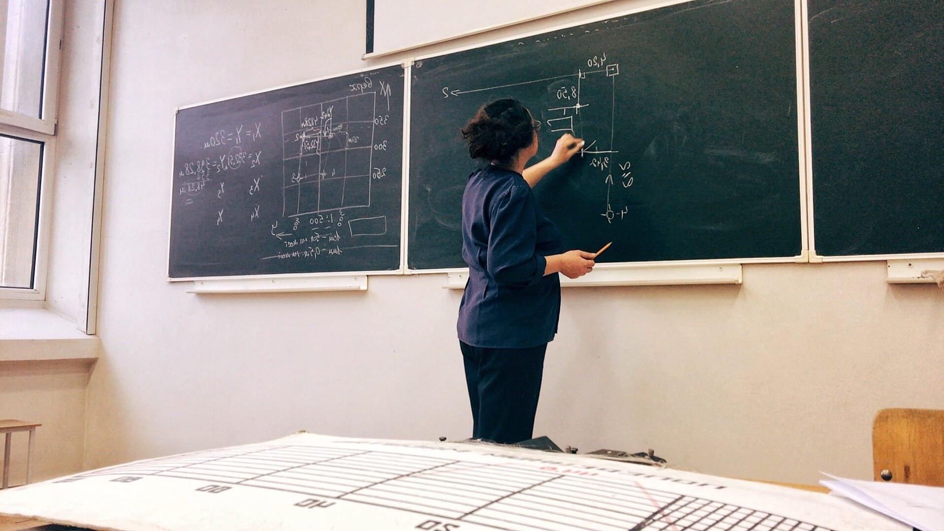 一个女人站在黑板前，用粉笔在黑板上写了一个数学方程式